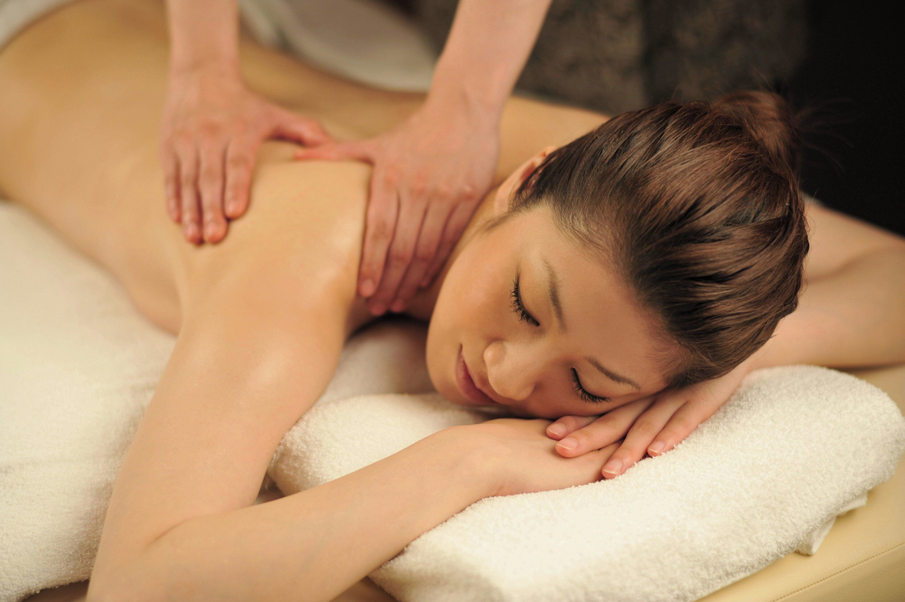A person receiving a back massage on a white towel.