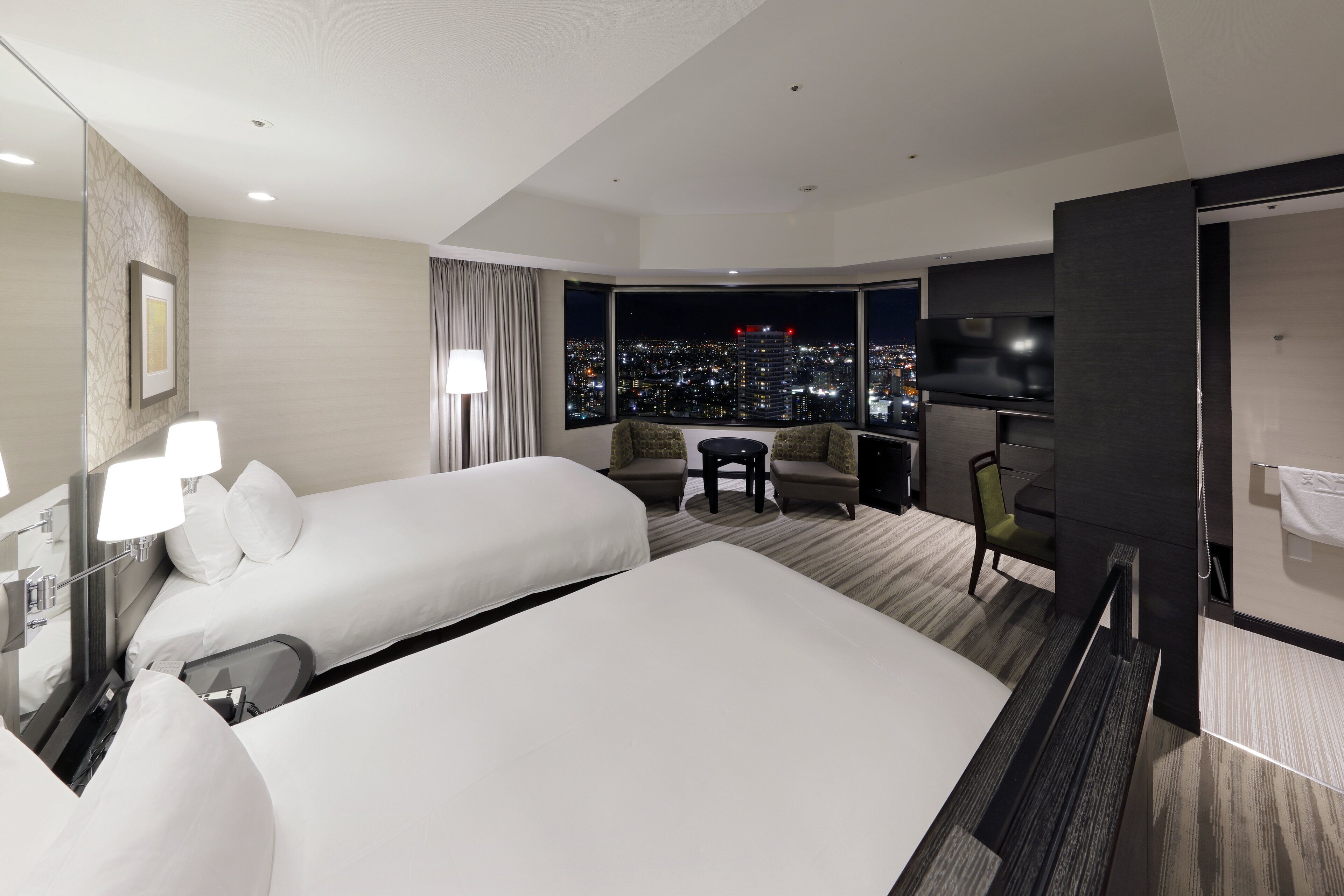 Una habitación de hotel con dos camas, un sofá, una mesita y un televisor.