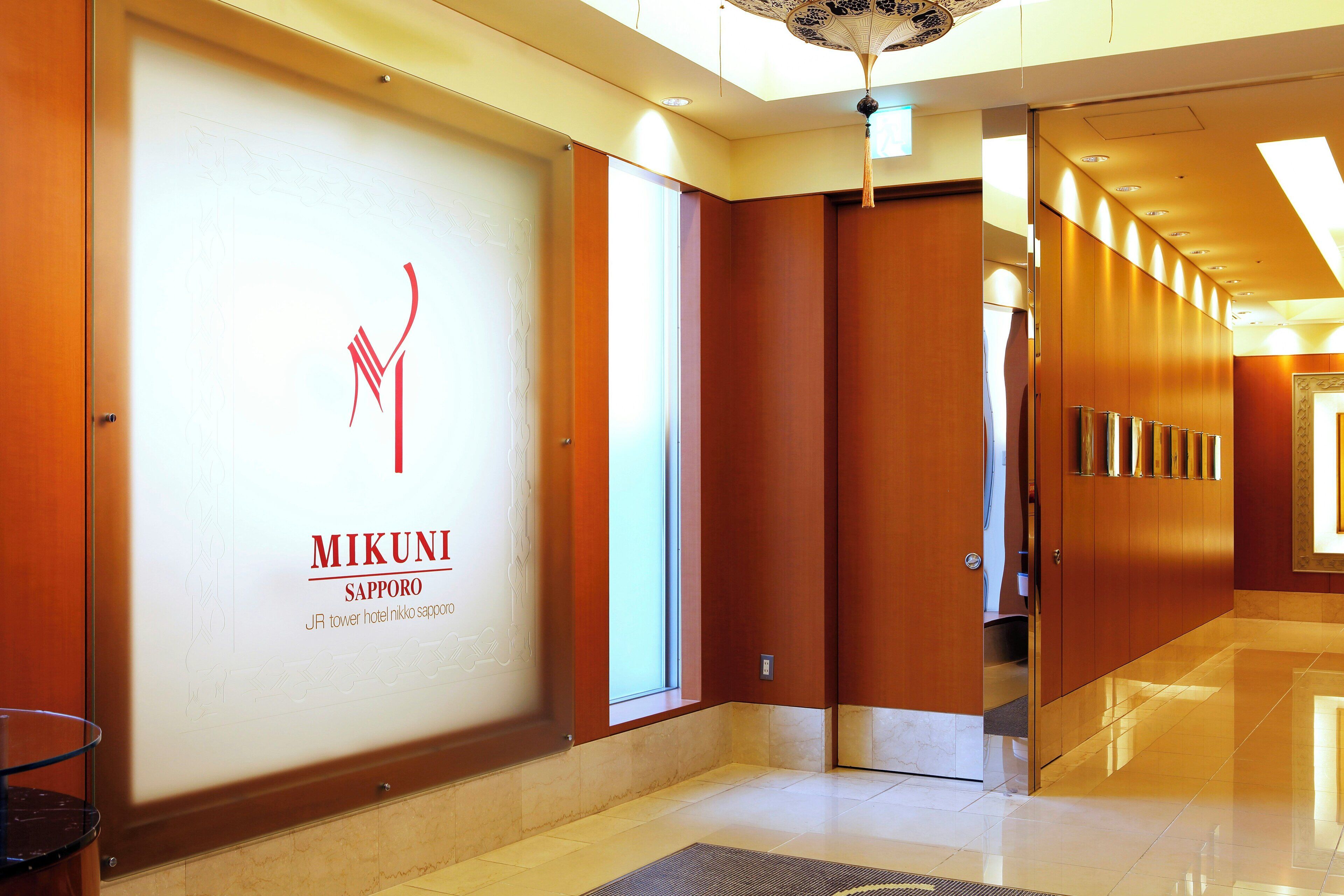 A hotel lobby with a large sign for 'MIKUNI SAPPORO' and a modern interior design.