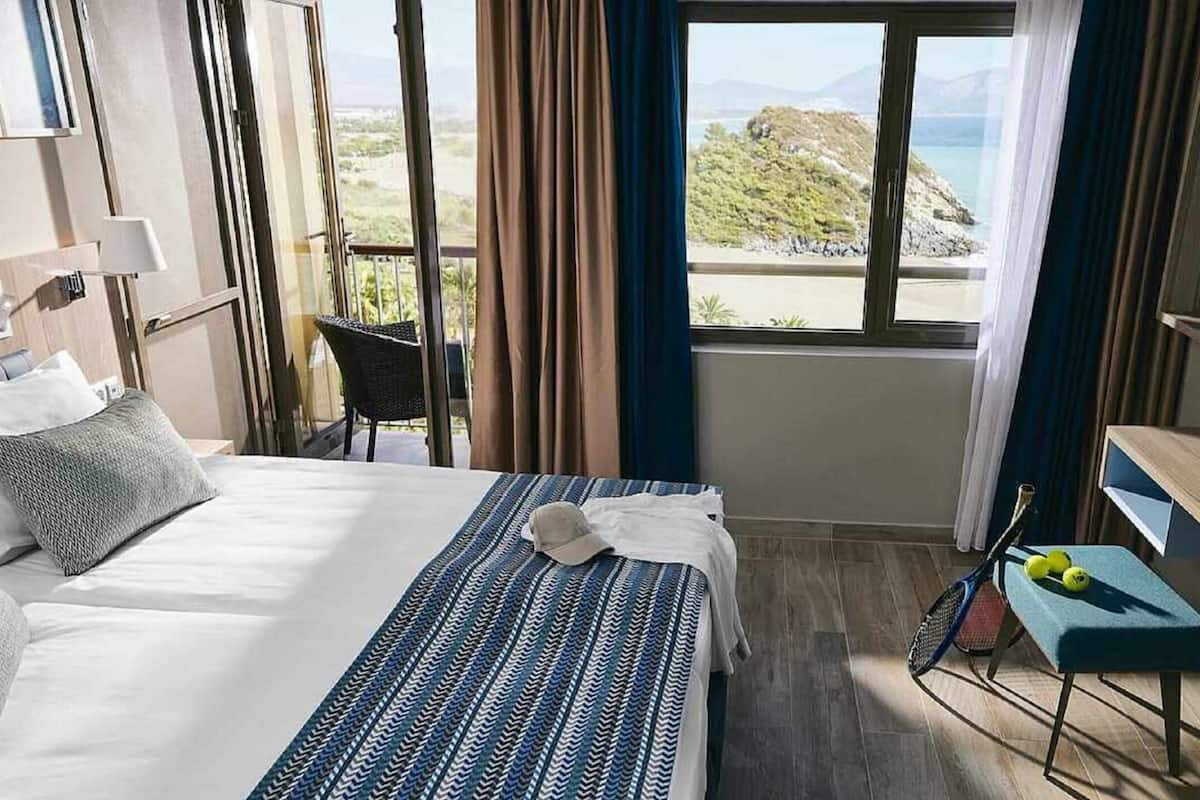Ein Hotelzimmer mit Bett, Sessel, Schreibtisch und Blick ins Freie.