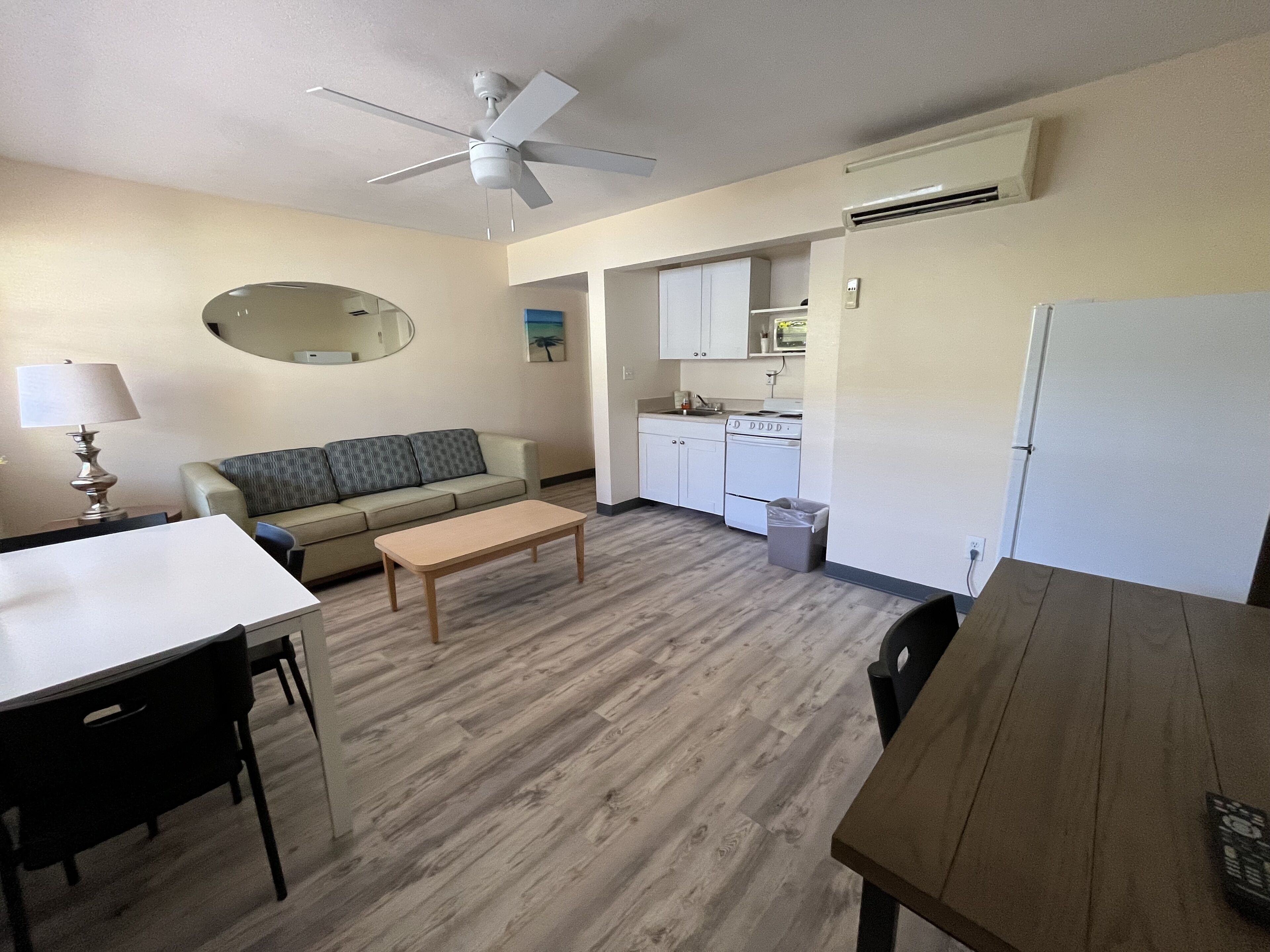 Un espace de vie compact comprenant un coin cuisine, un canapé, une table à manger et un ventilateur de plafond.