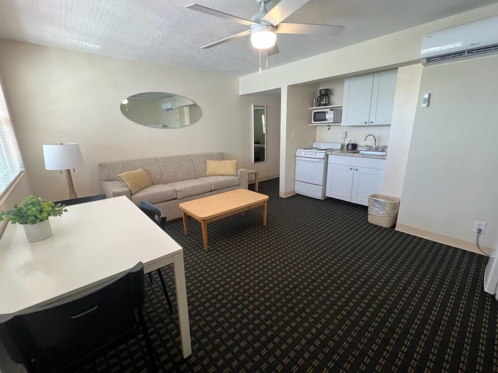 A compact living space with a kitchenette, a sofa, a dining table, and a ceiling fan.