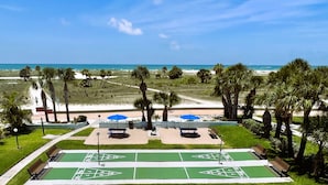 A park with green shuffleboard courts, benches, and palm trees. - Beachside Resort Motel (Treasure Island)