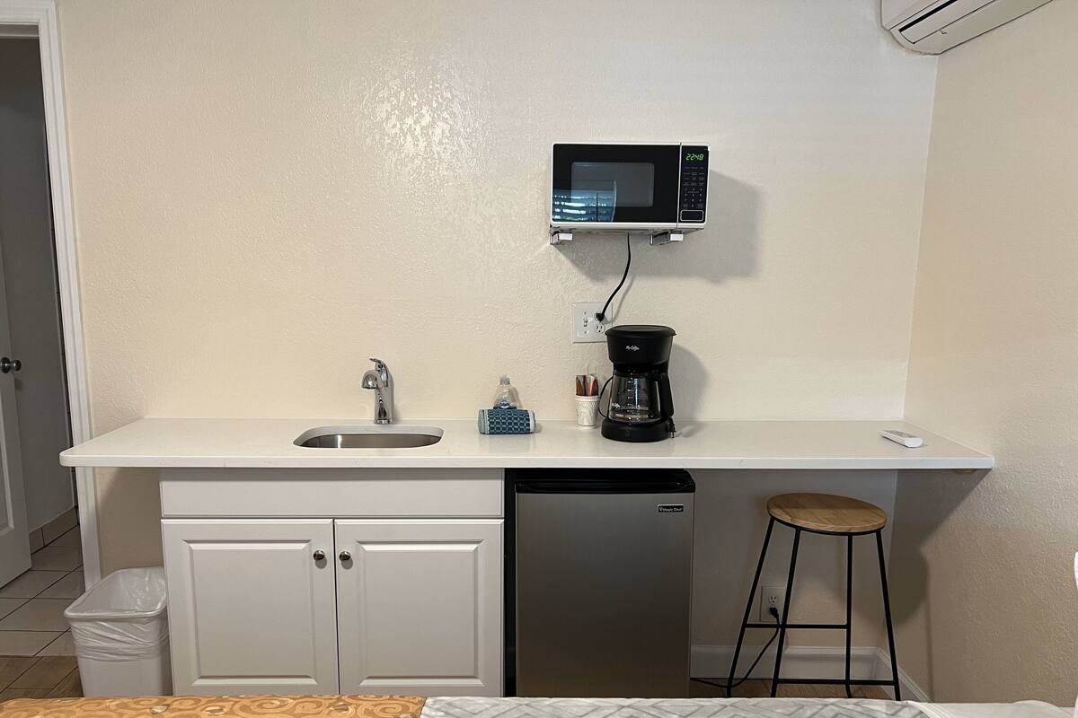 A compact kitchenette with a microwave, coffee maker, and sink.