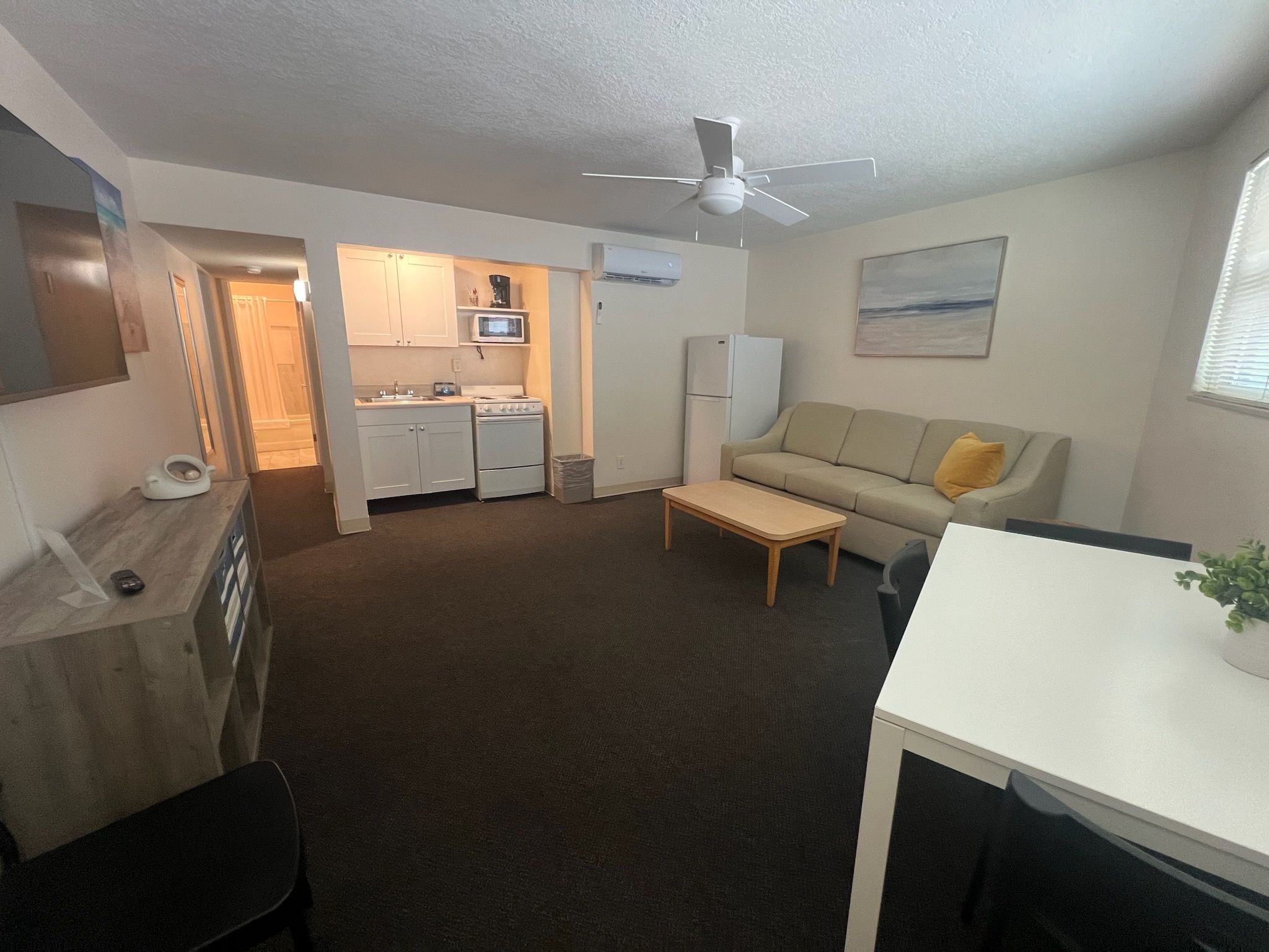 A compact living space with a kitchenette, a sofa, a coffee table, and a ceiling fan.
