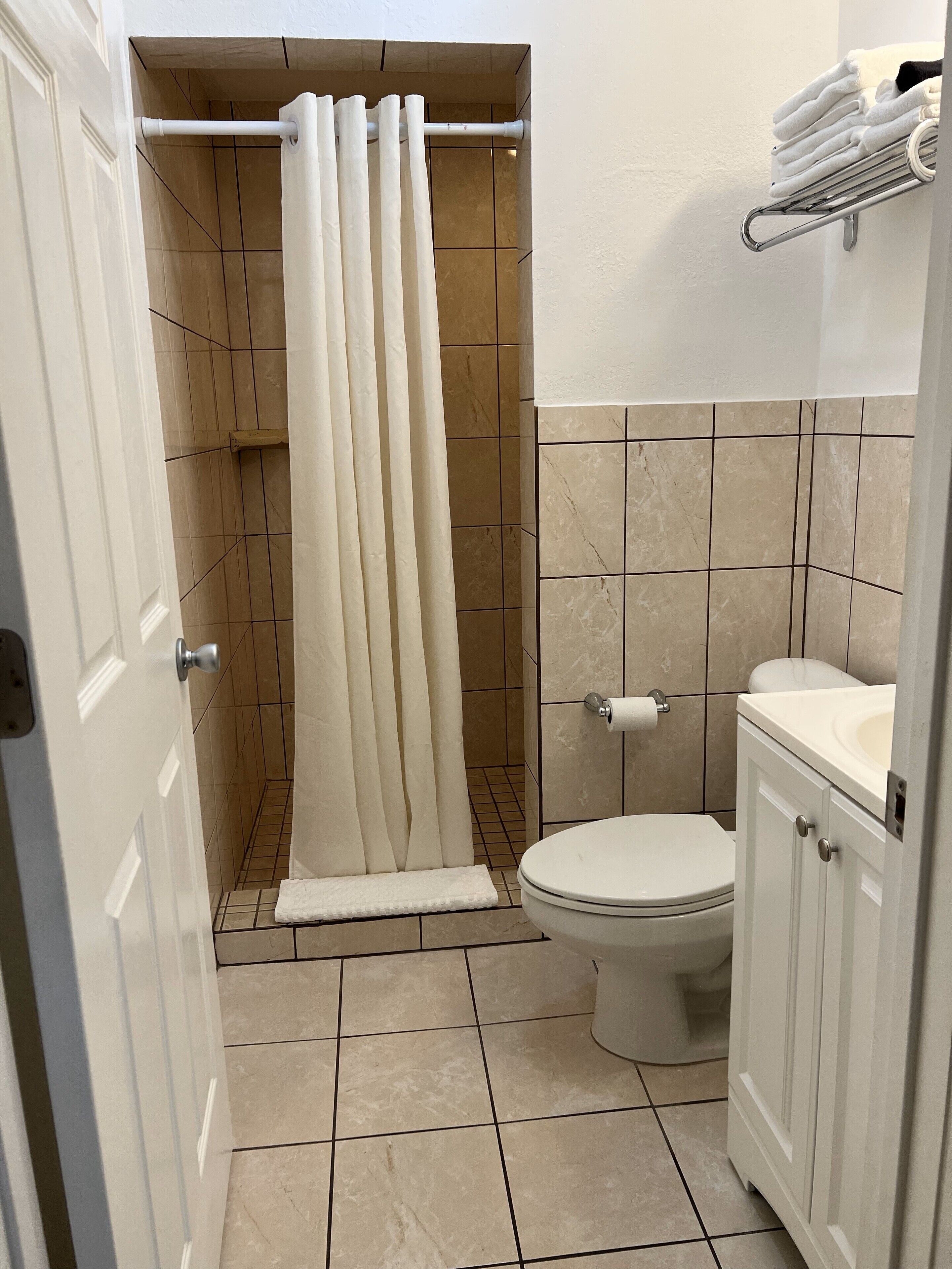 Un baño con cortina de ducha, inodoro y lavamanos.