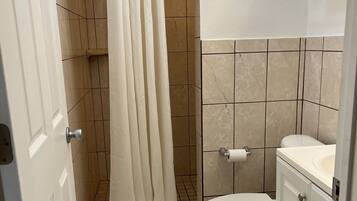 Un baño con cortina de ducha, inodoro y lavamanos.