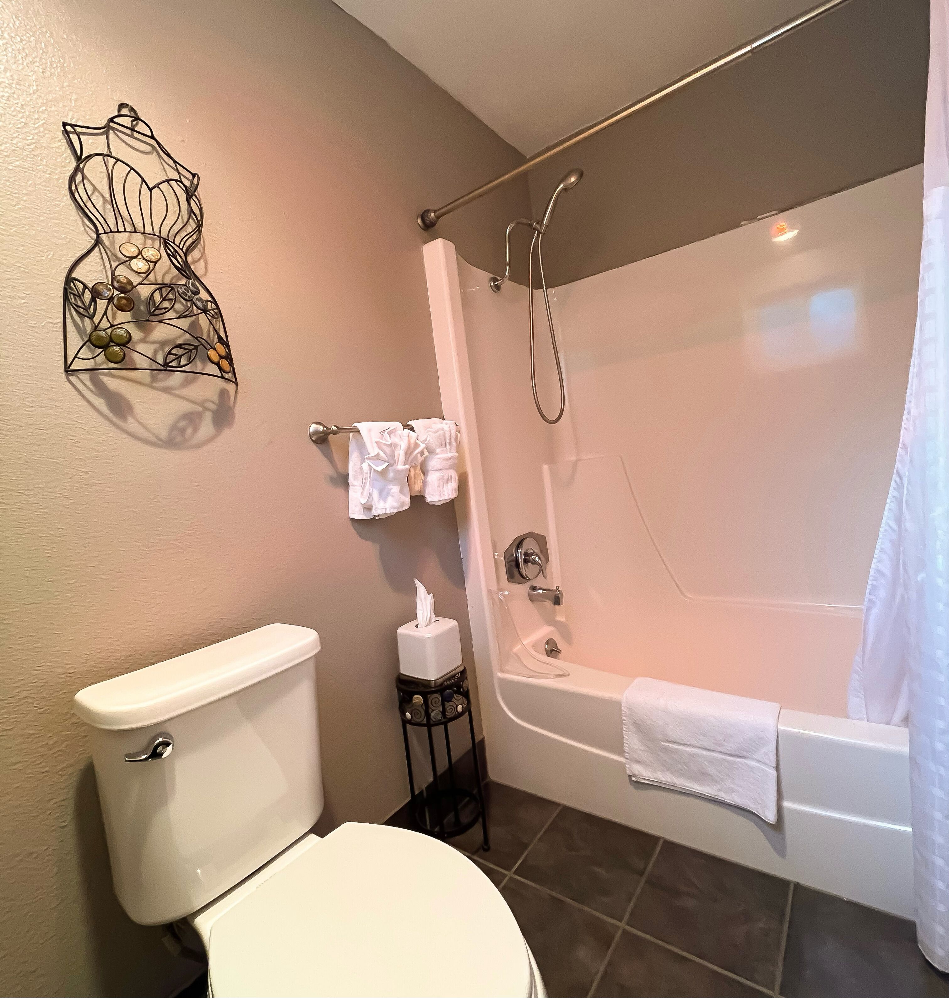 Ein Badezimmer mit Toilette, Badewanne, Handtuchhalter und einer dekorativen Wandverziierung.