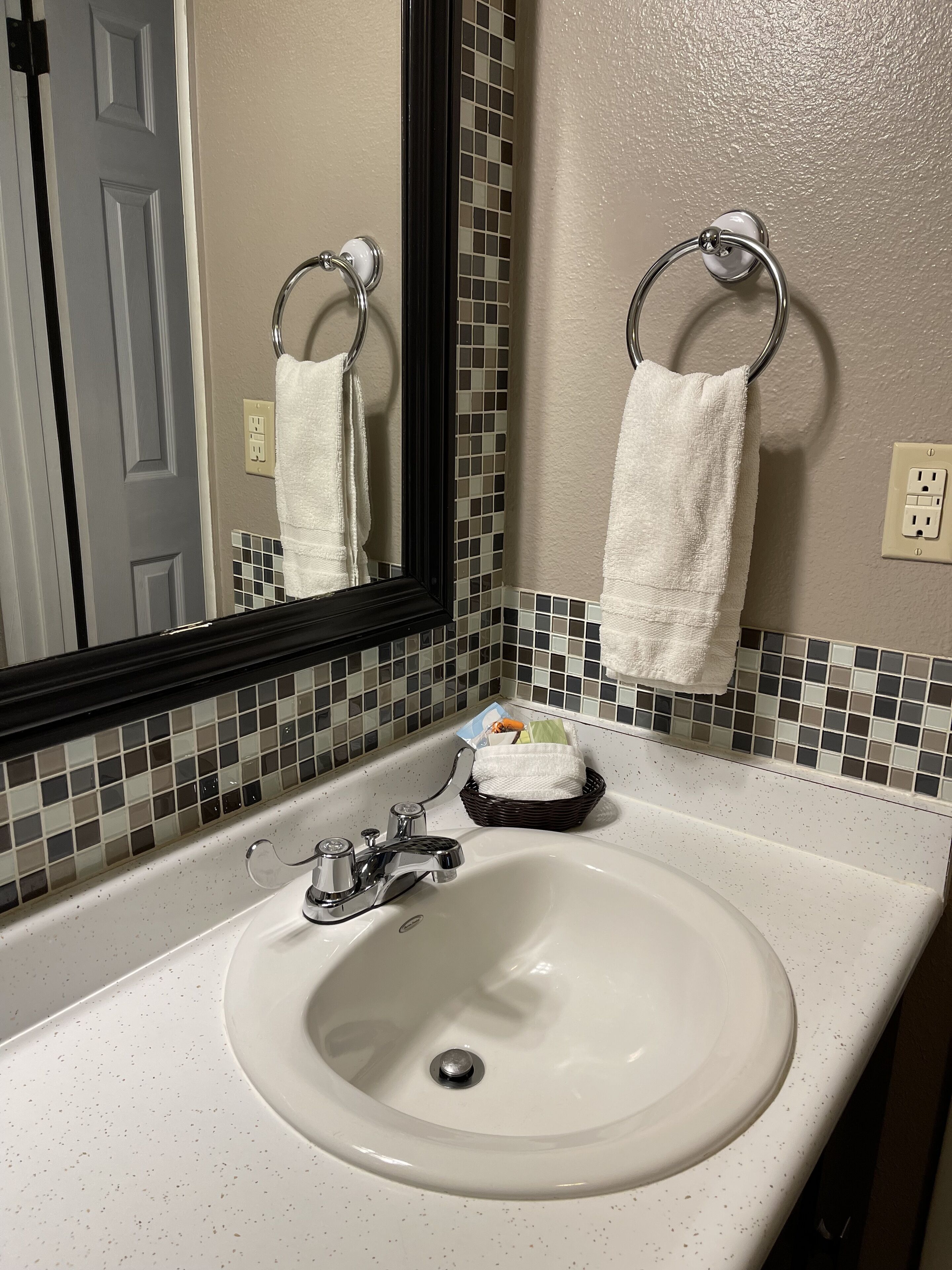 Un baño con lavamanos blanco, un espejo y salpicadero de azulejos.