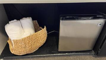 Un petit appareil métallique, peut-être une machine à café, est posé à côté d’un panier en osier contenant des serviettes pliées.