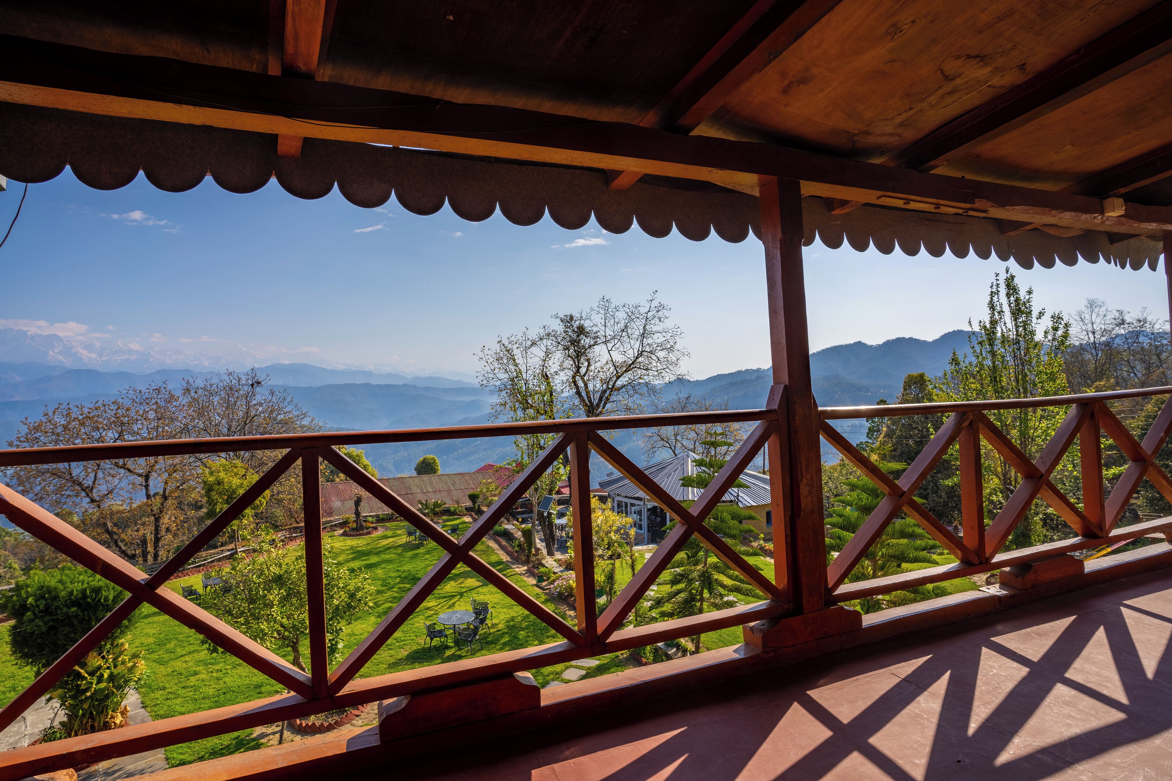 Un balcón de madera con vistas a un paisaje verde y montañas.