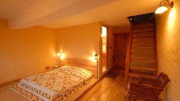 Un dormitorio con una cama de madera, una mesita de noche, una silla de madera y una escalera.