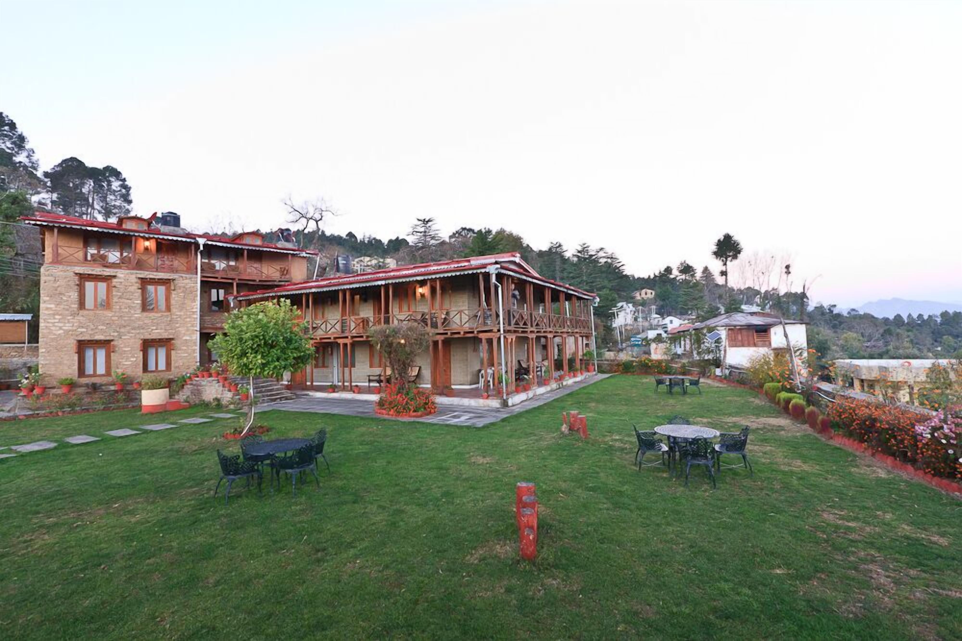 A two-story building with a wooden exterior and a balcony. There are outdoor seating areas with tables and chairs.