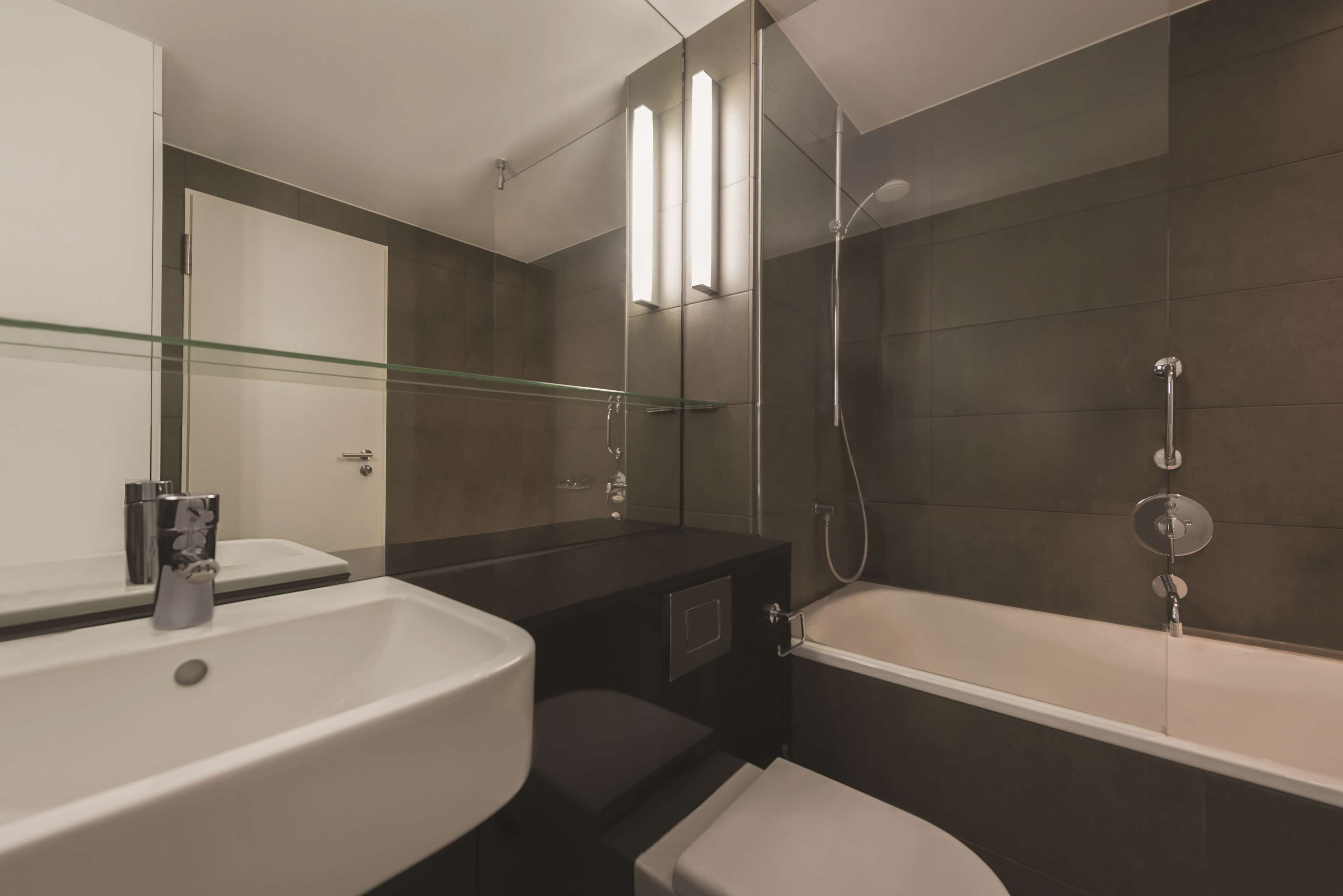 Une salle de bain moderne avec une douche à parois de verre, une baignoire blanche et un grand miroir au-dessus du lavabo.