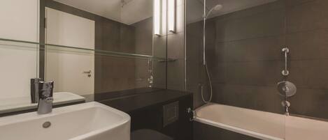 A modern bathroom with a glass shower enclosure, a white bathtub, and a large mirror above the sink.