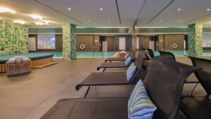 A modern indoor pool area with lounge chairs and a small pool. - Adina Apartment Hotel Hamburg Michel (Hamburg)