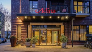 A modern building with a prominent 'Adina' sign above the entrance. - Adina Apartment Hotel Hamburg Michel (Hamburg)