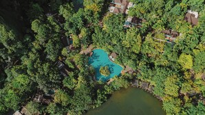 An aerial view of a resort with a central swimming pool surrounded by dense greenery and a small lake. - The Banjaran Hotsprings Retreat (Ipoh)