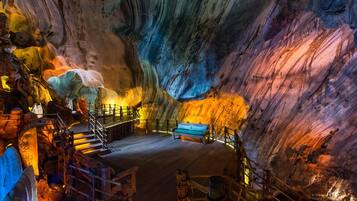 A cave interior with a wooden bench and a staircase leading to an upper level.