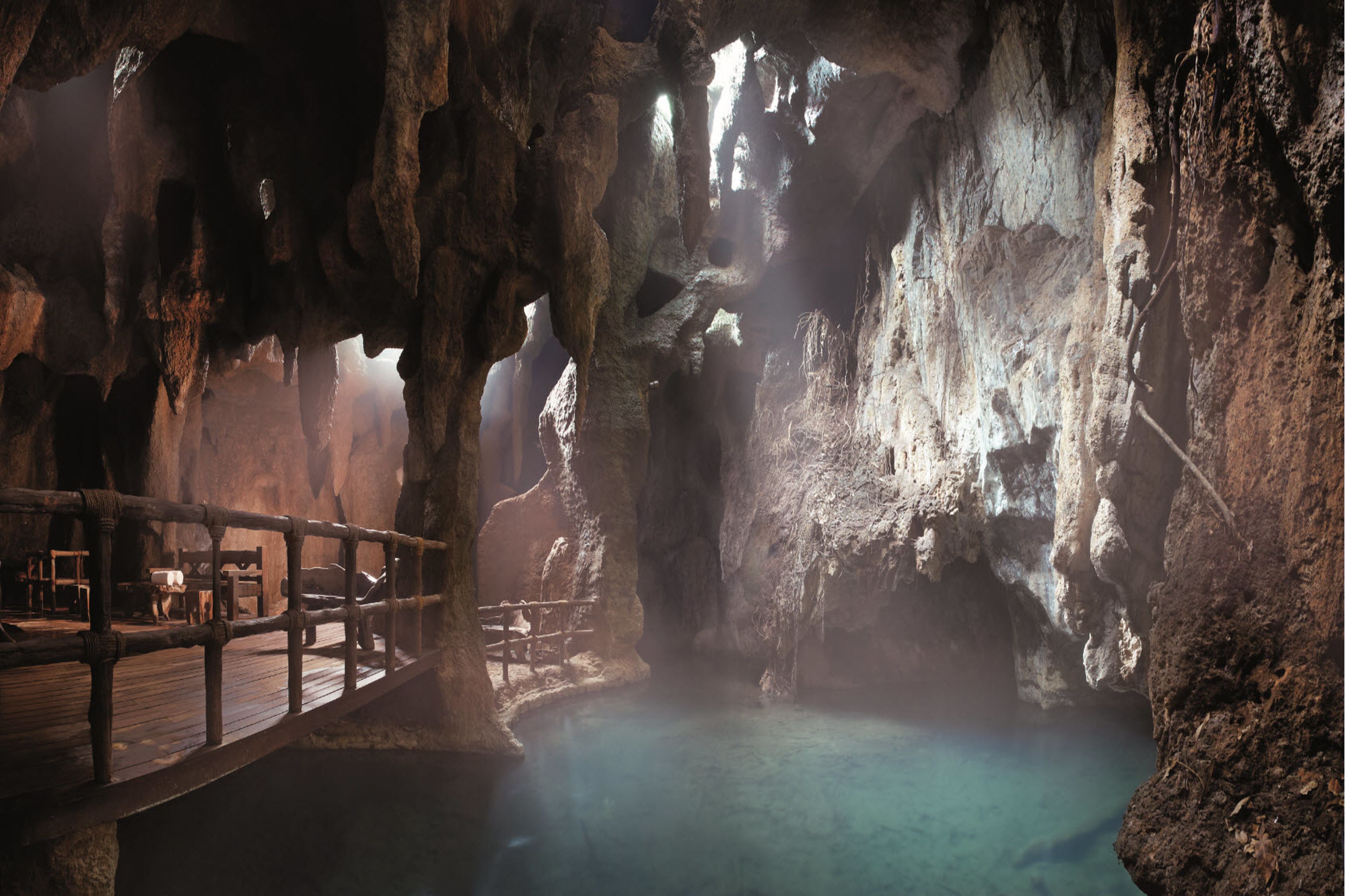 A cave interior with a wooden deck and a clear pool.
