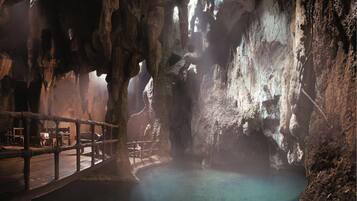 A cave interior with a wooden deck and a clear pool.