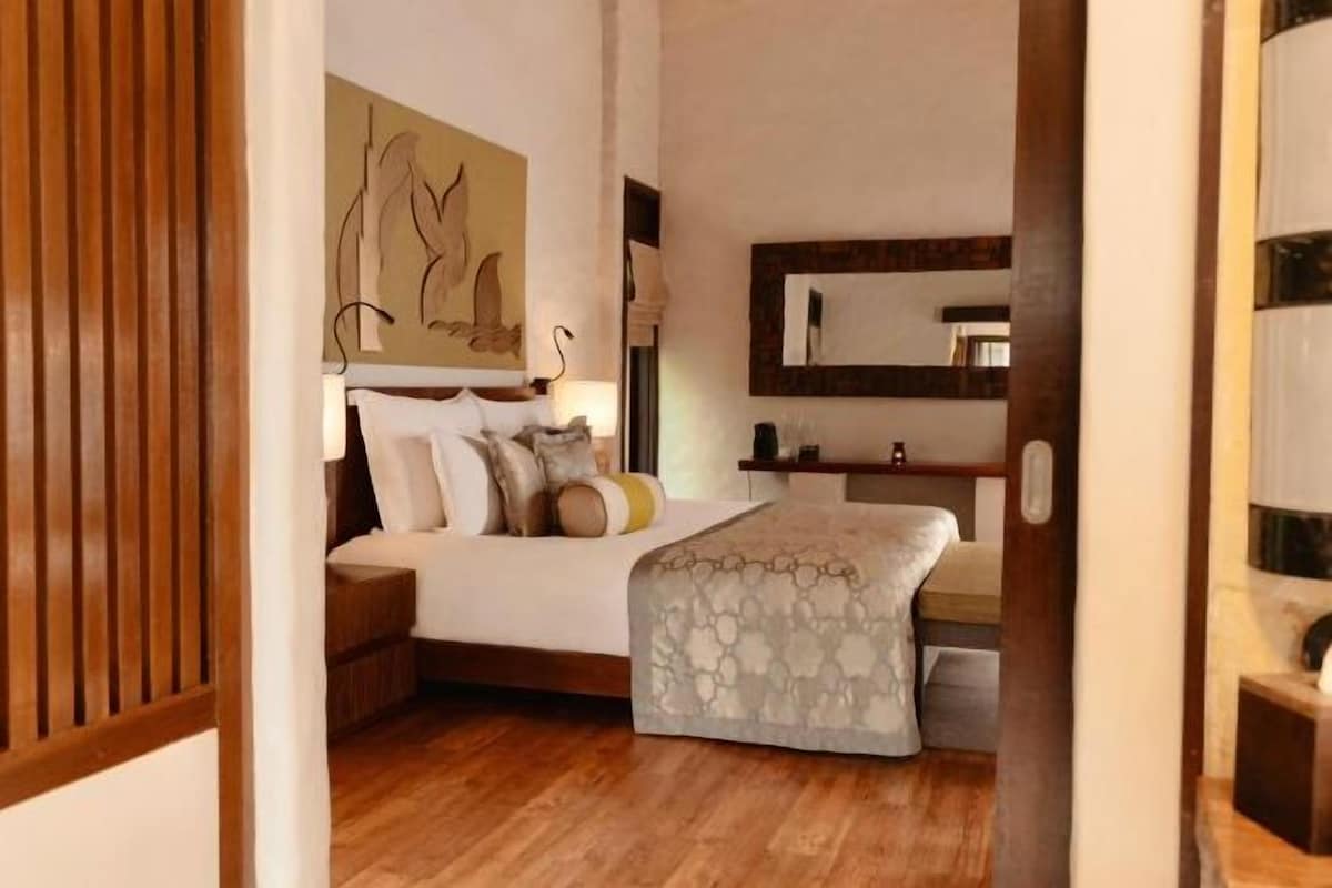 Un dormitorio con cama, mesitas de noche, un espejo y un cuadro en la pared.