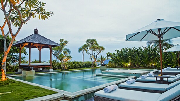A poolside area with lounge chairs, a gazebo, and a view of the ocean.