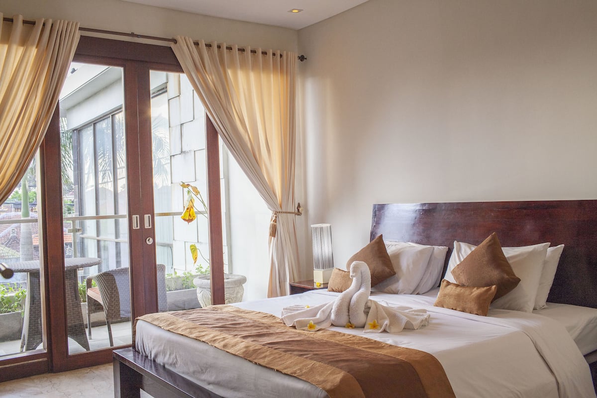 A hotel room with a bed, a bench, a table, and a chair.