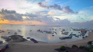 A beach with boats, a gazebo, and a hut.