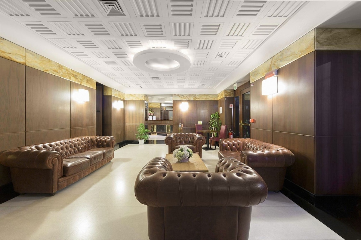 Un rebedor ampli amb sofàs de cuir, una taula de cafè central i una planta decorativa.