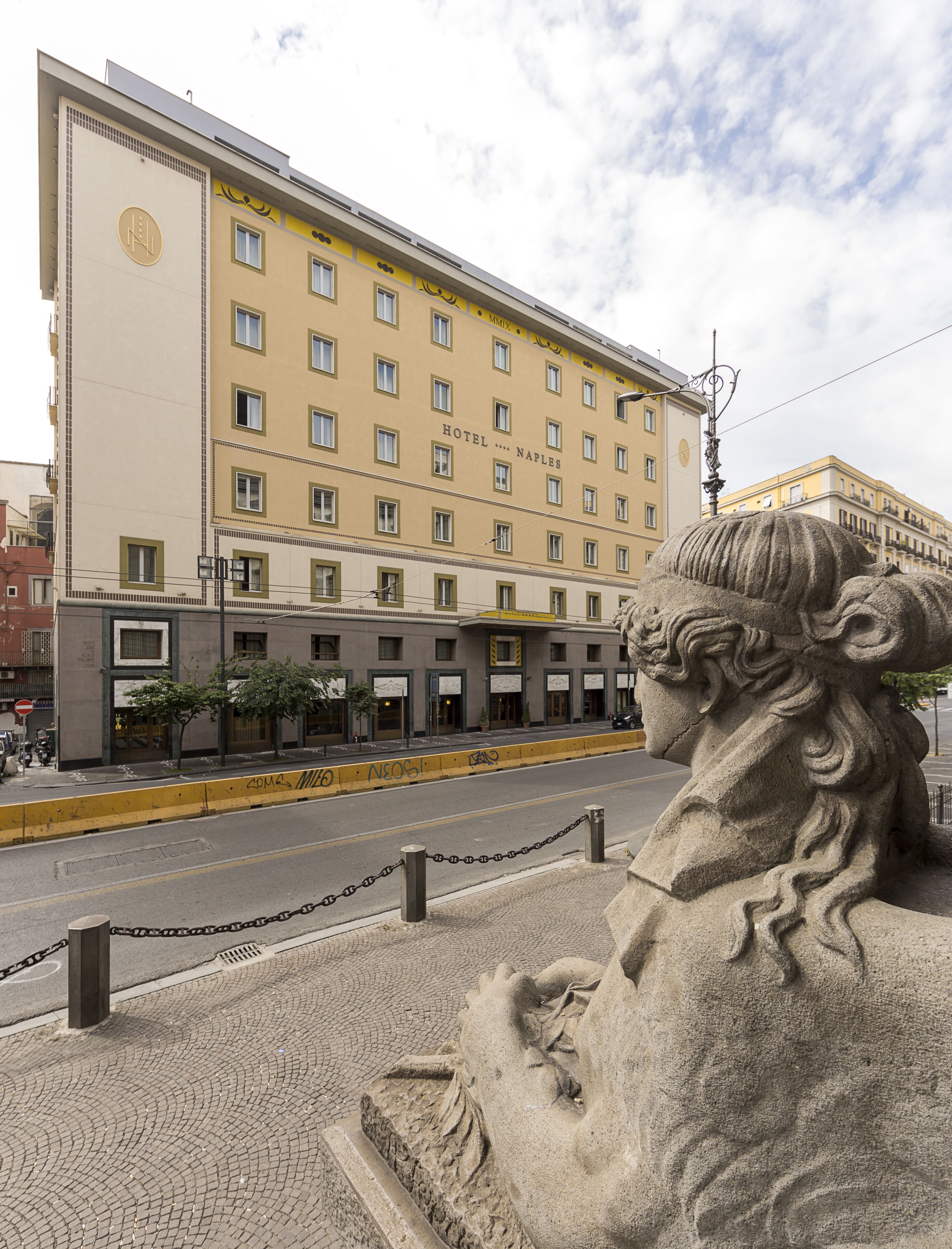 Un edificio de hotel con varios pisos, una entrada destacada y una estatua al frente.