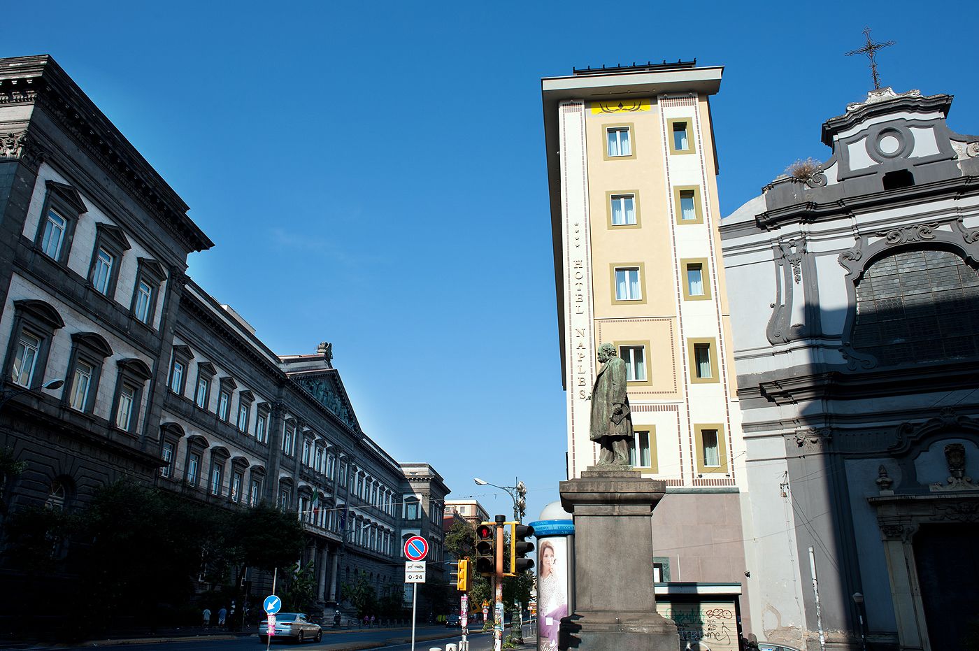 Une vue de rue avec des bâtiments historiques, une statue et des panneaux de signalisation.