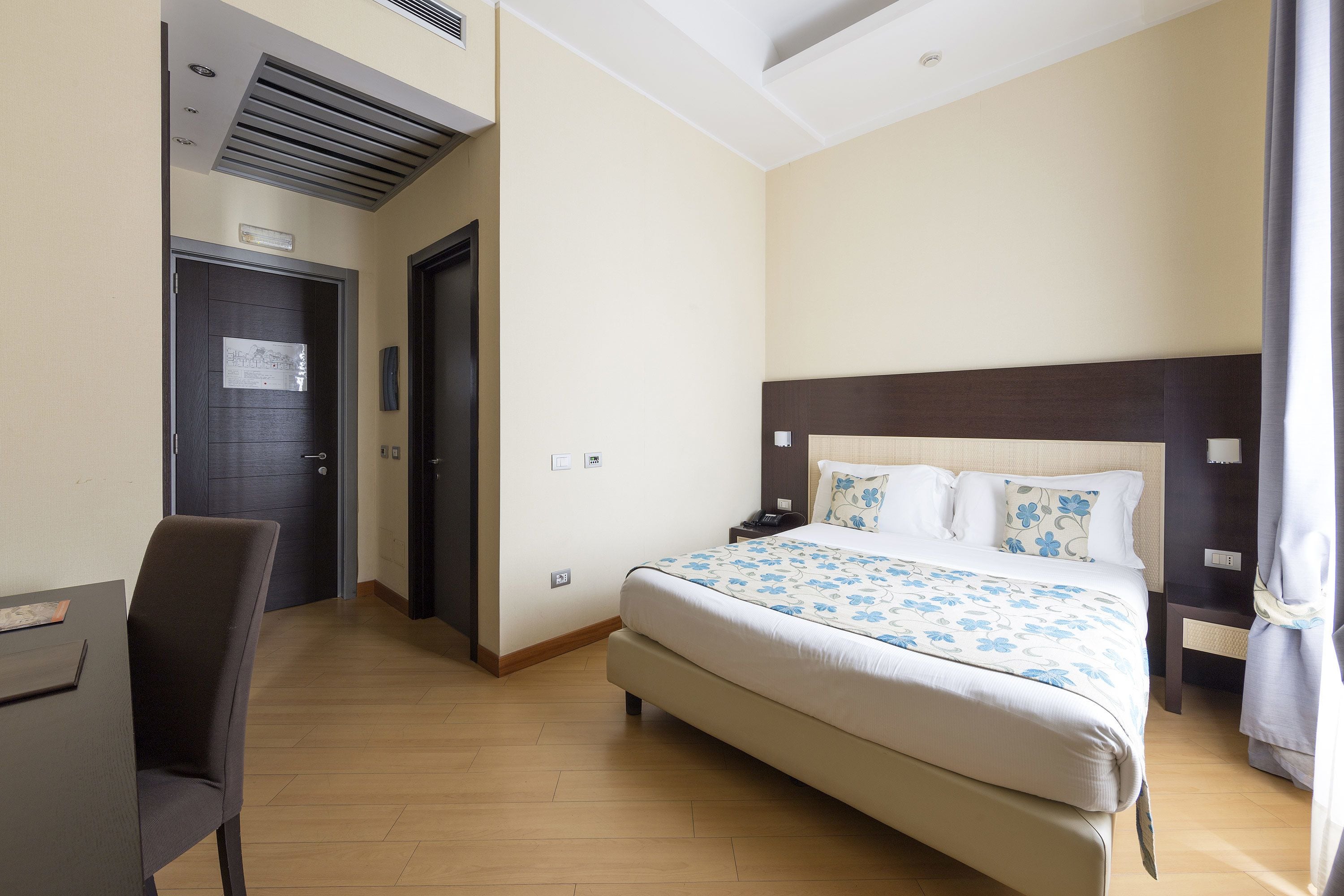 Hotellihuone, jossa on sänky, työpöytä ja tuoli.