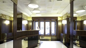 Un moderno vestíbulo de hotel con un mostrador de recepción curvo, ventanas amplias y un techo alto con iluminación empotrada.