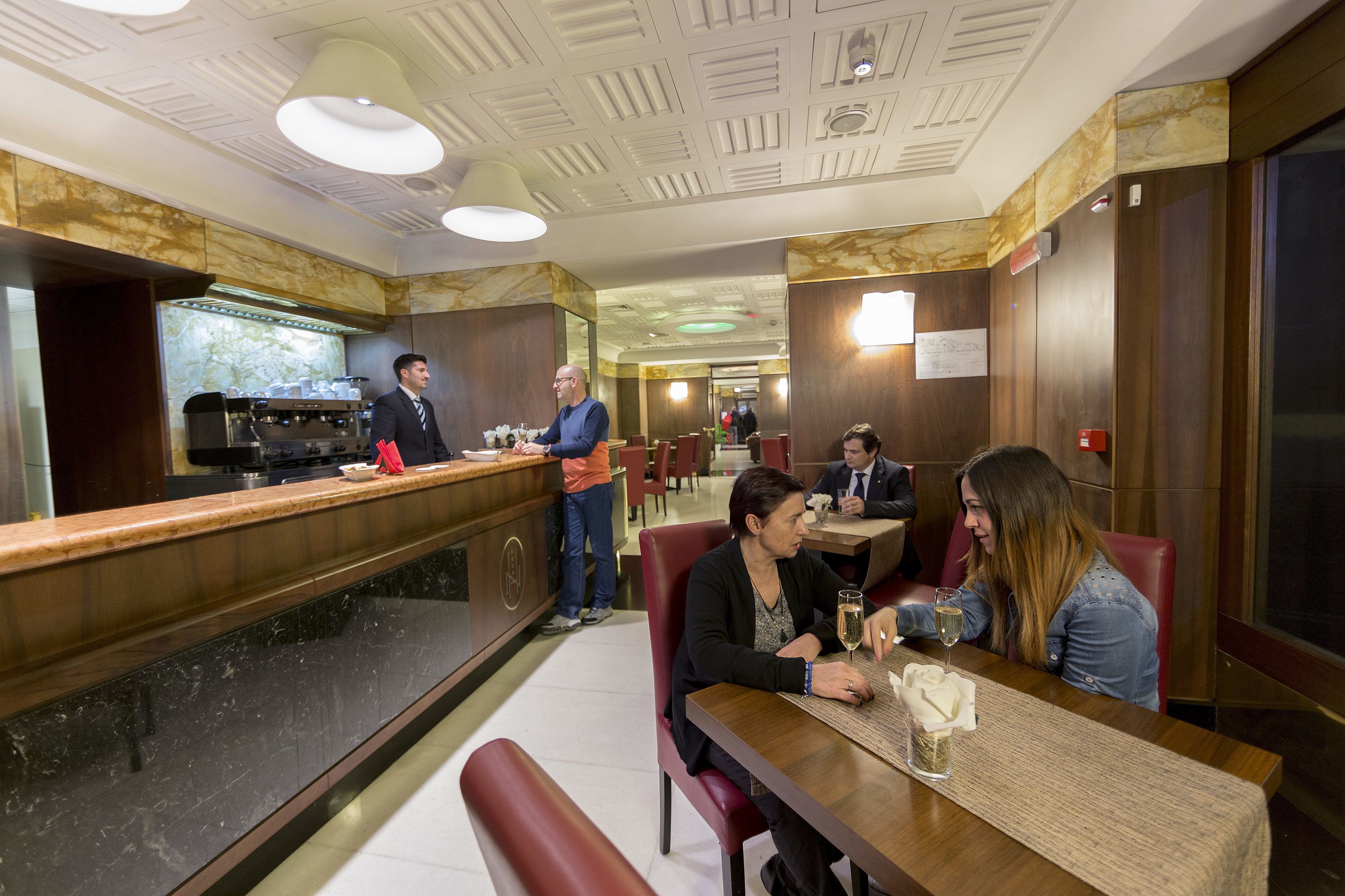 A restaurant with a marble counter, wooden paneling, and a modern ceiling design.