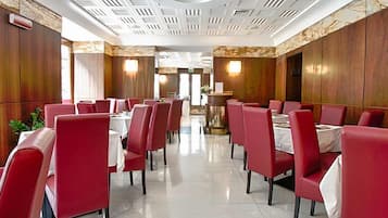 En restaurant med røde stole, hvide duge, en sleben gulv og et dekorativt loft.