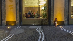 Un edificio con un amplio acceso de vidrio, un hidrante y una calle adoquinada.