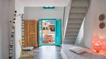 Staircase leads to an upper level, with a dining area and a single bed positioned against the wall.