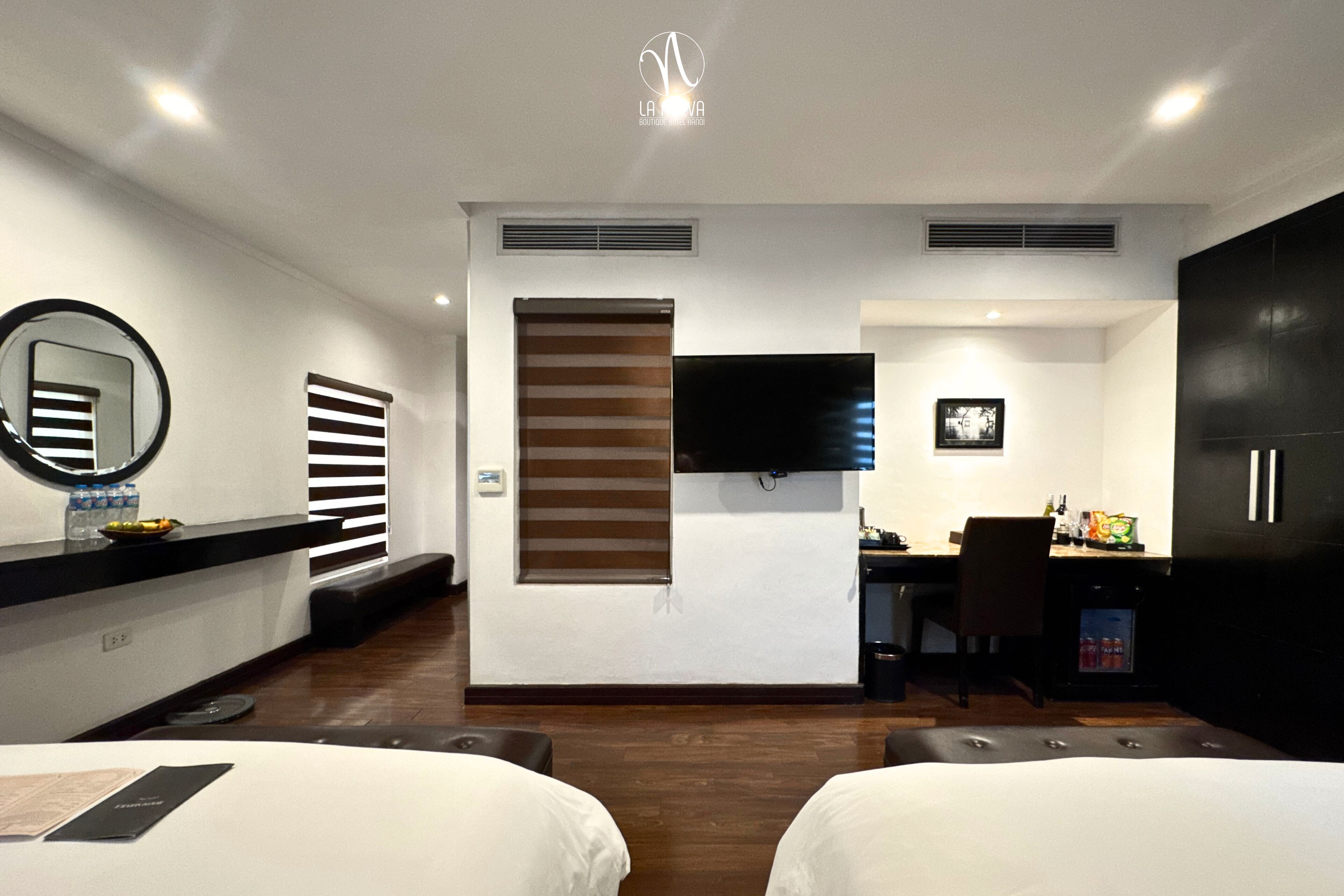 Ein modernes Hotelzimmer mit Bett, Schreibtisch, Fernseher und Minibar.