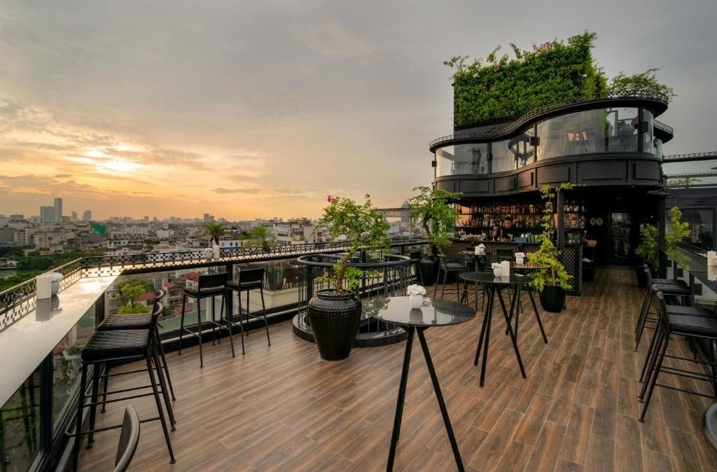 A rooftop bar with outdoor seating, a city view, and a curved glass structure.