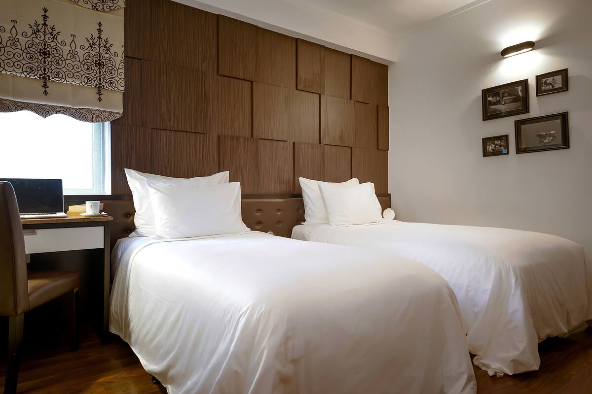 Une chambre d’hôtel avec deux lits, un bureau et une chaise.
