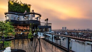 Un bar situé sur le toit d’un immeuble, offrant une vue sur la ville, avec un espace bar et des places assises en plein air.