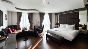 Une chambre d’hôtel moderne dotée d’un grand lit, d’un bureau, d’un coin salon et d’un grand miroir.