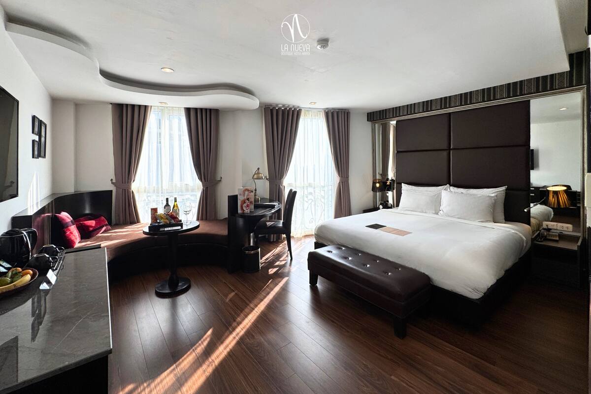 Une chambre d’hôtel moderne dotée d’un grand lit, d’un bureau, d’un coin salon et d’un grand miroir.