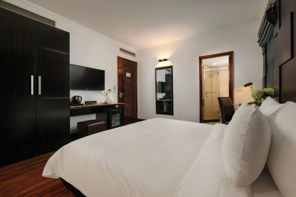 Une chambre d’hôtel équipée d’un lit, d’un bureau, d’une chaise, d’une télévision et d’un miroir.