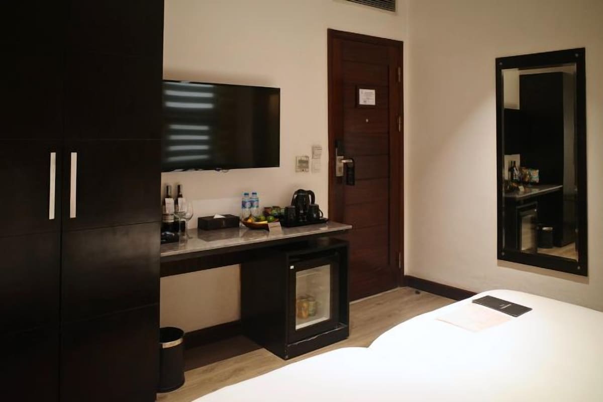 Une chambre d’hôtel comprenant un lit, un bureau avec un téléviseur à écran plat, une machine à café et un petit placard.