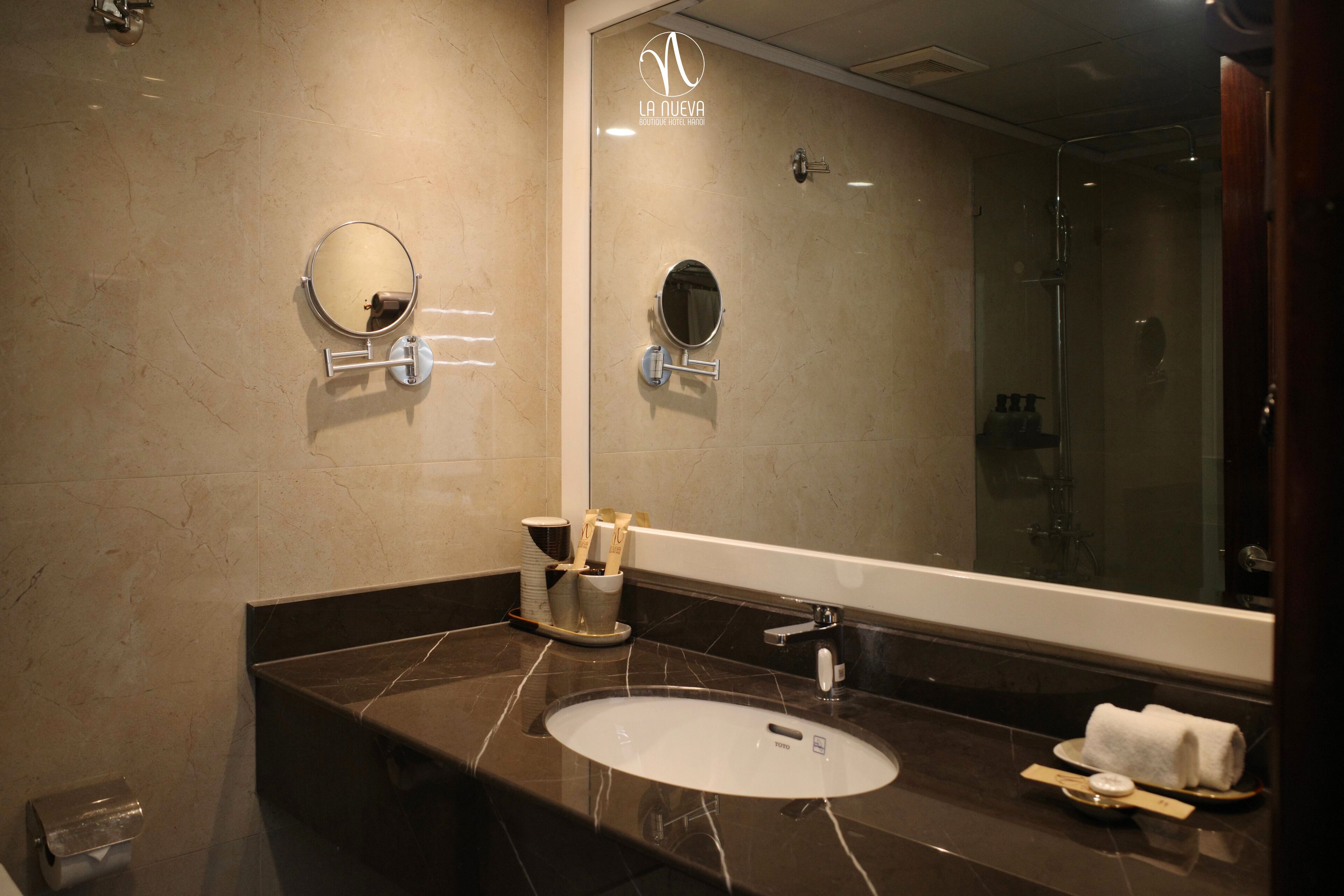 A modern bathroom with a large mirror, a sink, and a shower.