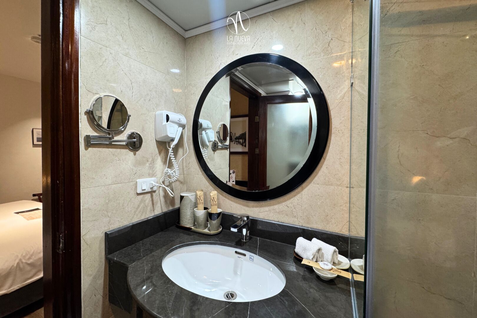 A modern bathroom with a round mirror, a white sink, and a hairdryer.
