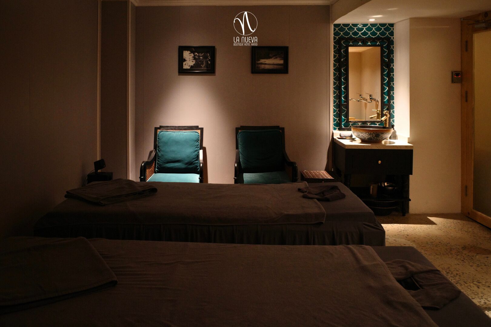 A hotel room with two beds, a desk with a mirror, and a small table with a bowl.