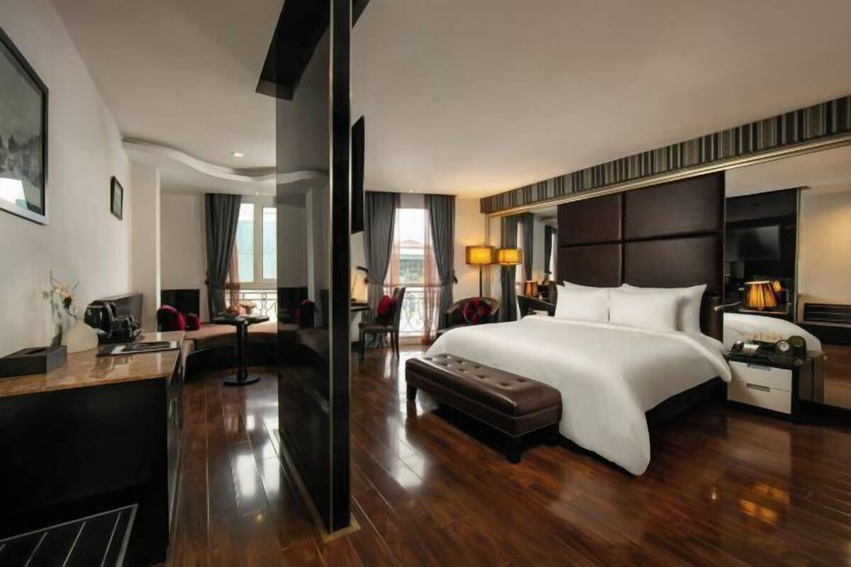 Une chambre d’hôtel avec un grand lit, un bureau, une chaise, un canapé et une télévision.
